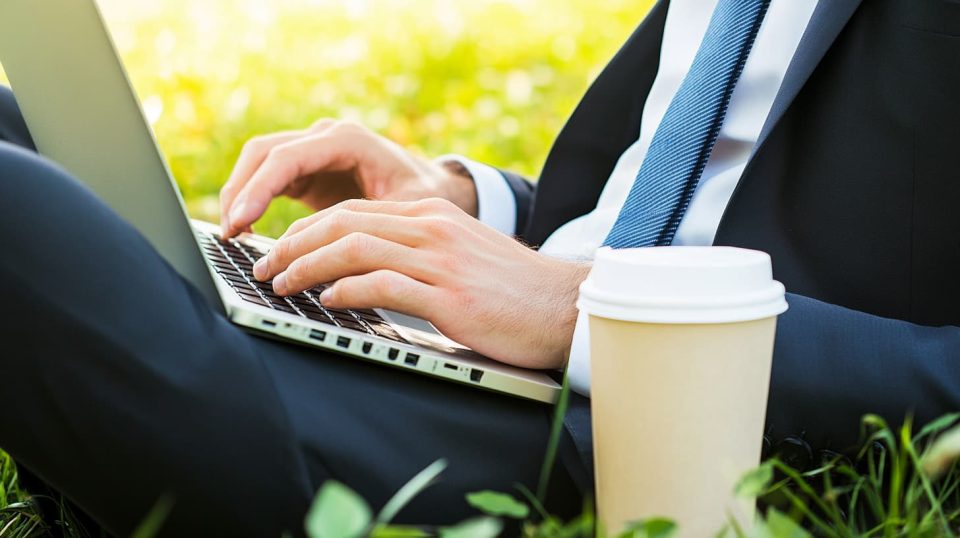 A professional in business attire studying on a laptop during a lunch break in a park, with a takeaway coffee beside them. ai generated